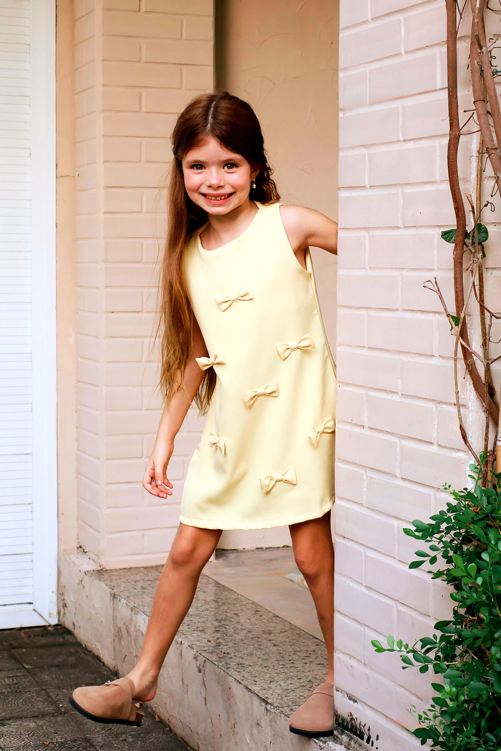 Menina sorrindo com vestido claro de lacinhos da Miki