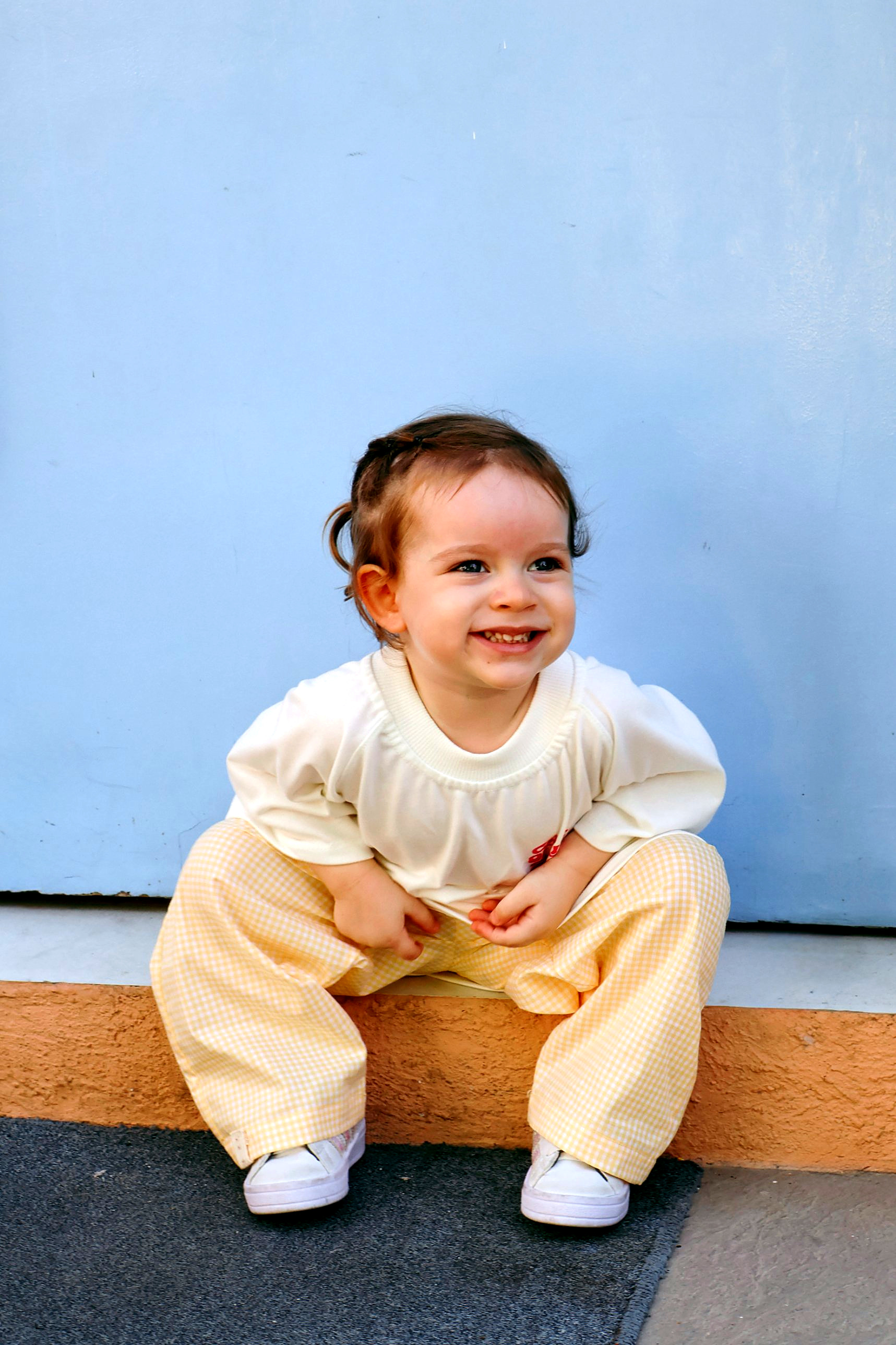Bebê sorrindo vestindo roupa da Miki em frente a uma parede azul